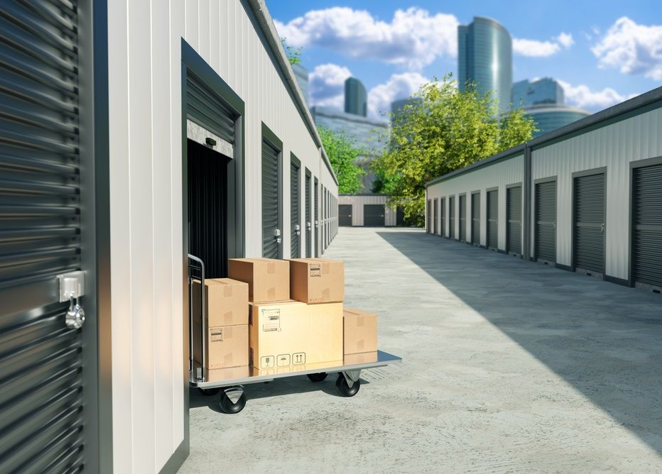 Storage facility alley with cardboard boxes on a hand truck beside garage doors