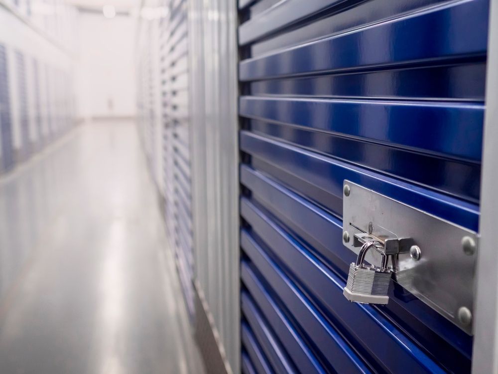 Blue storage unit door with padlock in a brightly lit storage facility hallway.
