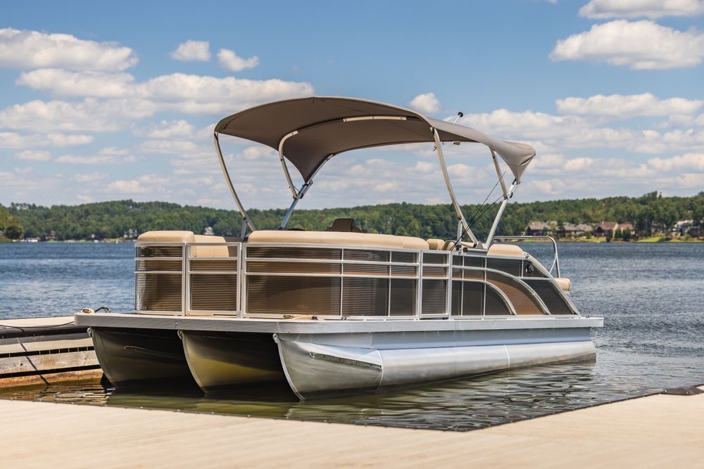 A pontoon boat is docked at a dock on a lake.