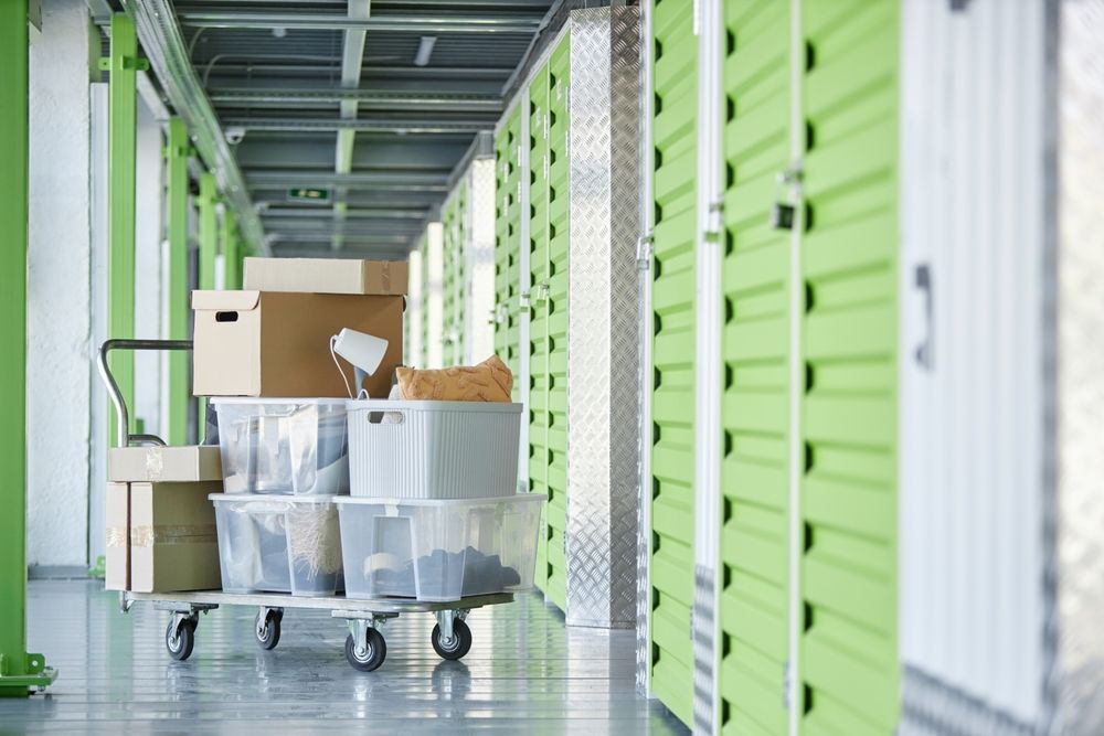 A hallway filled with green lockers and boxes on a cart.
