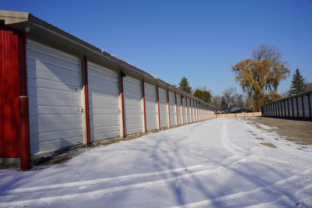 Snowy storage unit row with closed gray doors and a clear blue sky