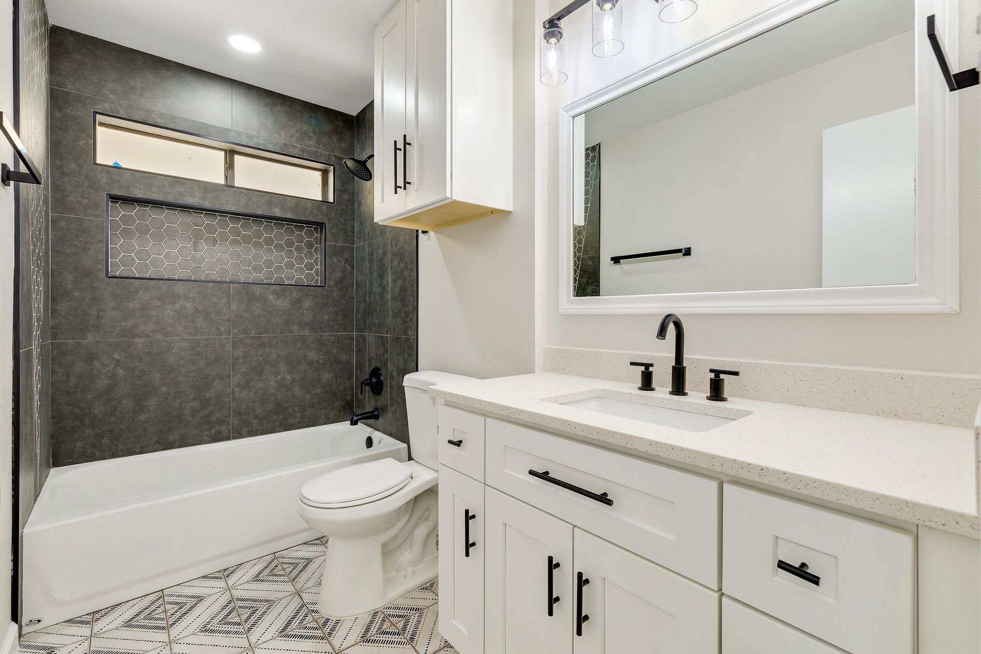 Custom Bathtub Tile Surround with modern plumbing fixtures included in bathroom renovation, quartz countertops, modern light fixtures and custom ceramic and porcelain tile installation in Highland Village Denton County Texas