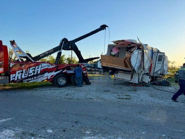 Severe crash scene with a tow truck lifting a damaged vehicle at dusk