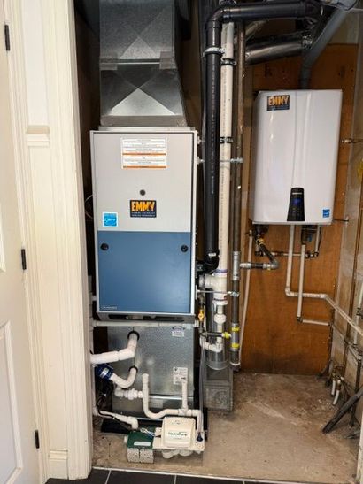 HVAC furnace and water heater in a narrow utility closet with exposed pipes and ducts