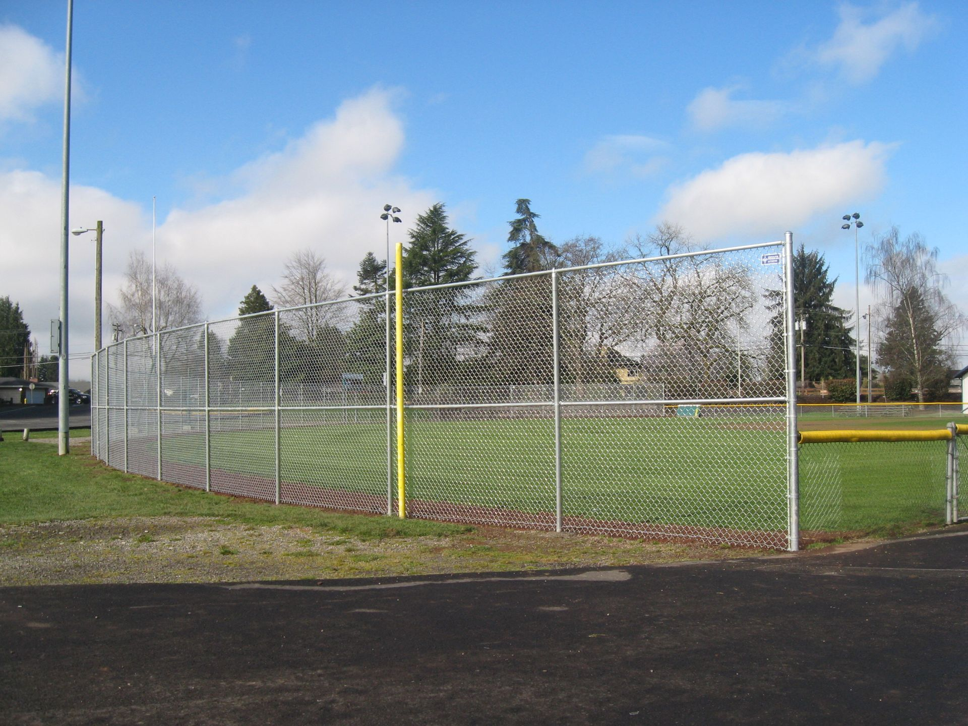 Empty outdoor sports field behind chain-link fence on a cloudy day