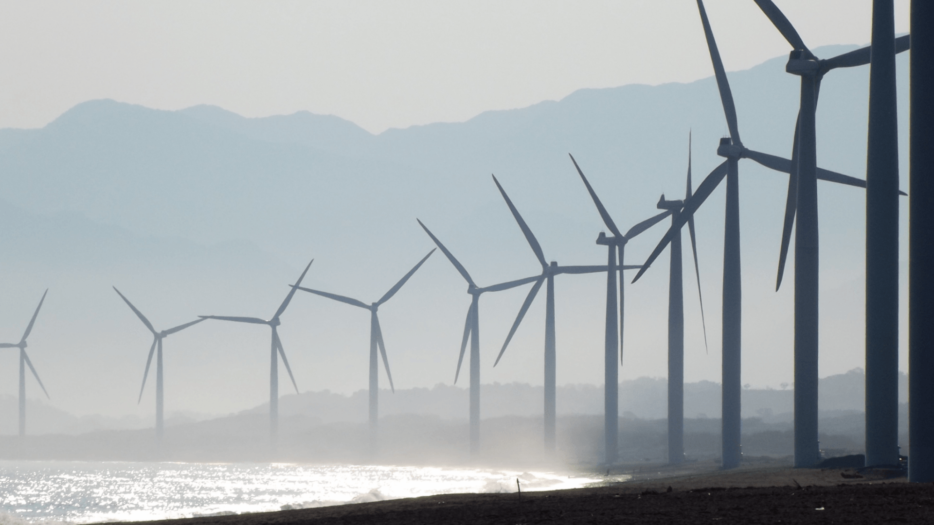 A row of wind turbines along a coast
