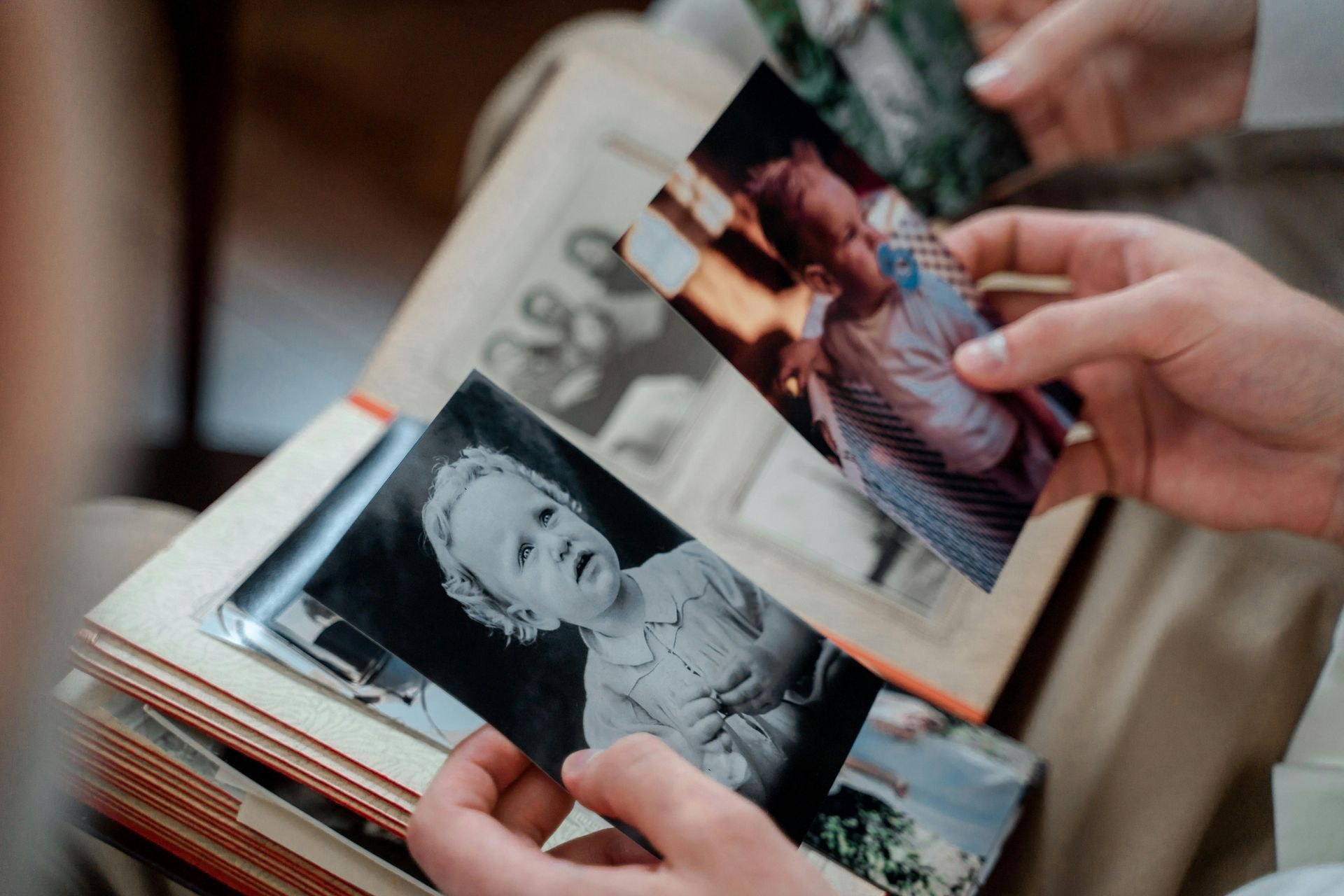 Hands sorting through a stack of printed family photos, including a black-and-white portrait.