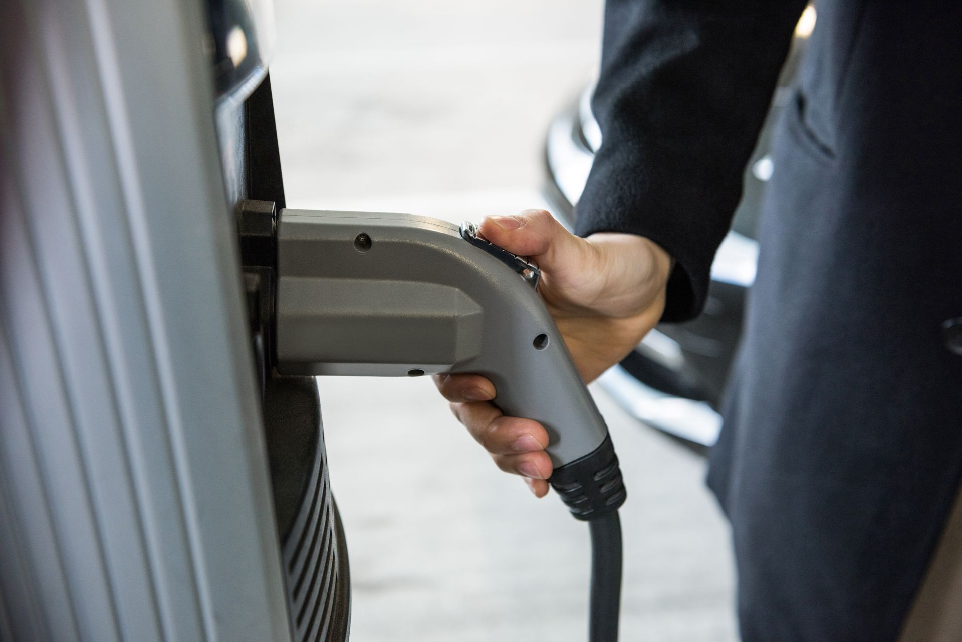 Person plugging an electric vehicle charging cable into a car.