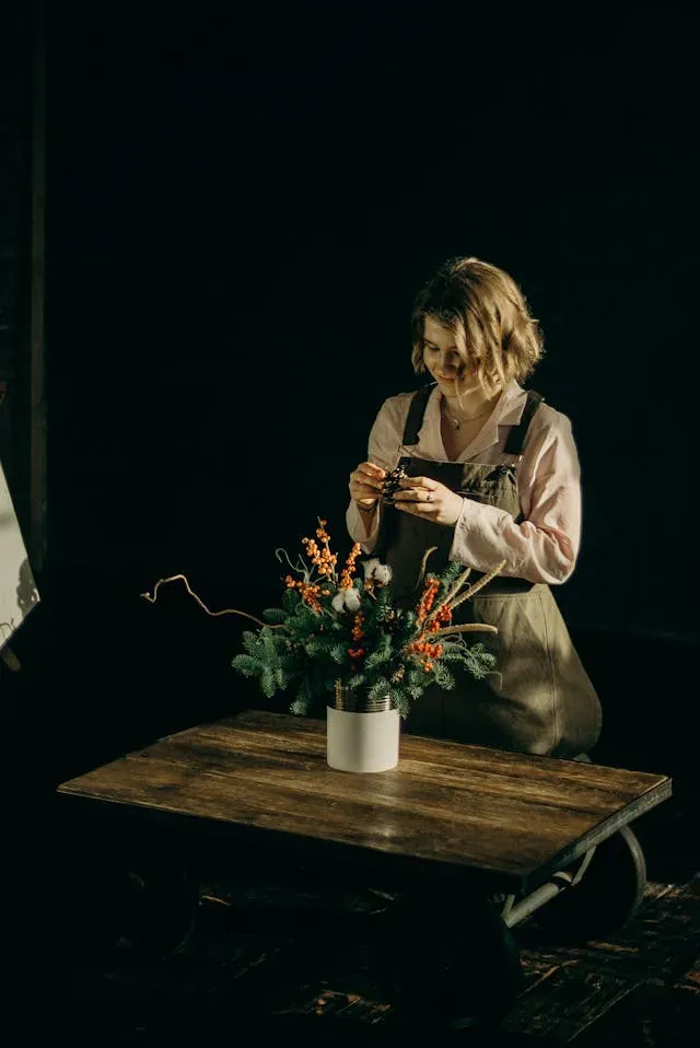 Une fleuriste arrange des fleurs dans un vase.