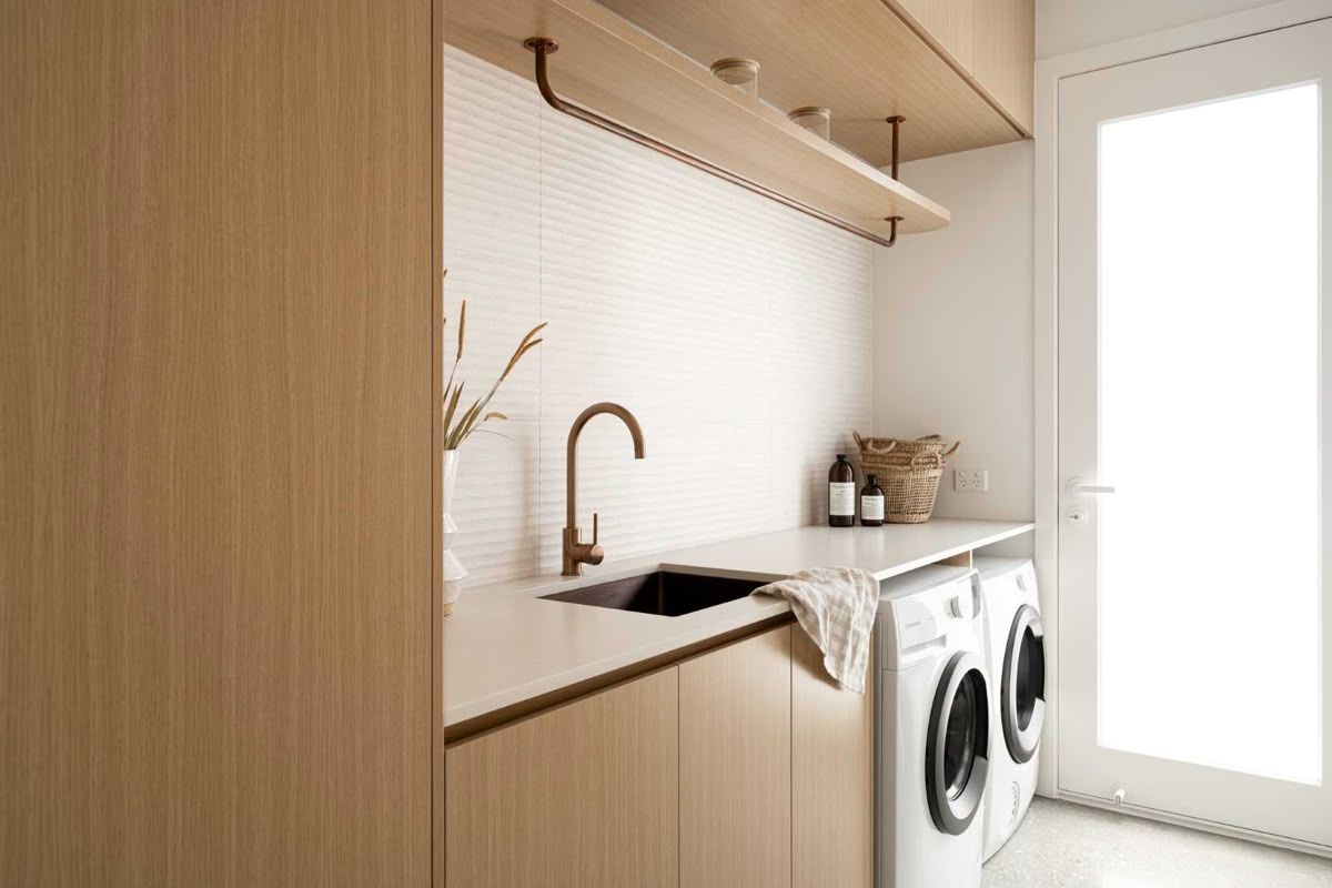 Bright Laundry Room With Wood Cabinets, Sink, and Front-loading Washer — Hinch Plumbing In Breakwater, VIC