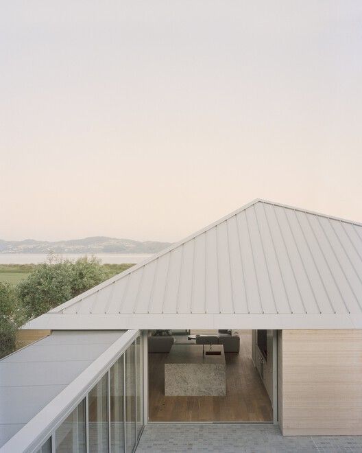 Modern House With a Gray Metal Roof, Open Walkway, and Distant Water View at Dusk — Hinch Plumbing In Breakwater, VIC