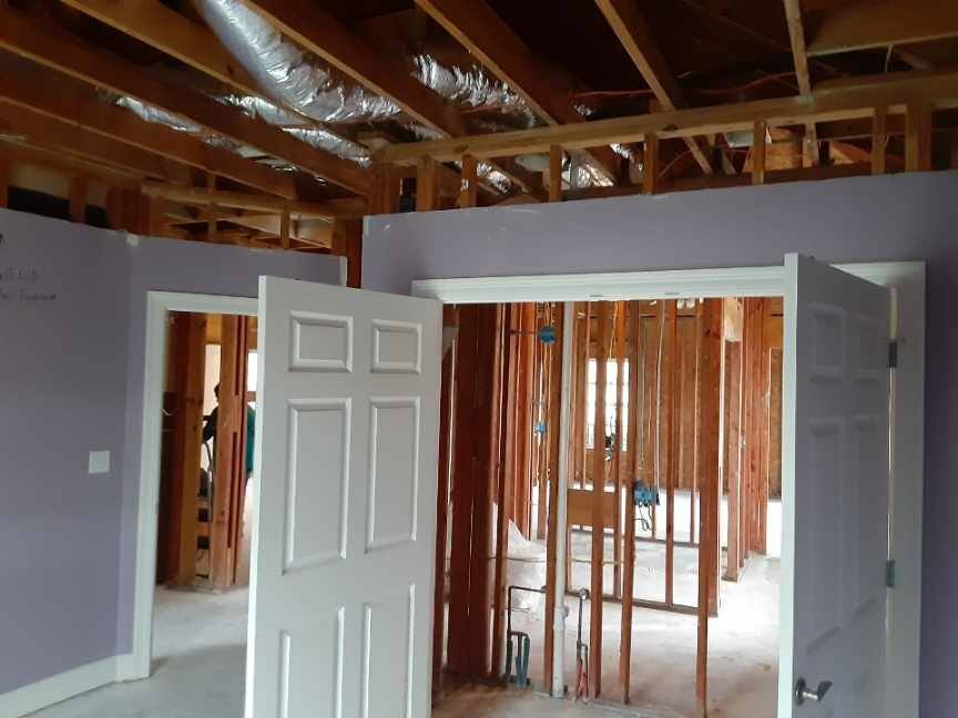 Partially finished room with exposed studs, open white doors, and a bare subfloor