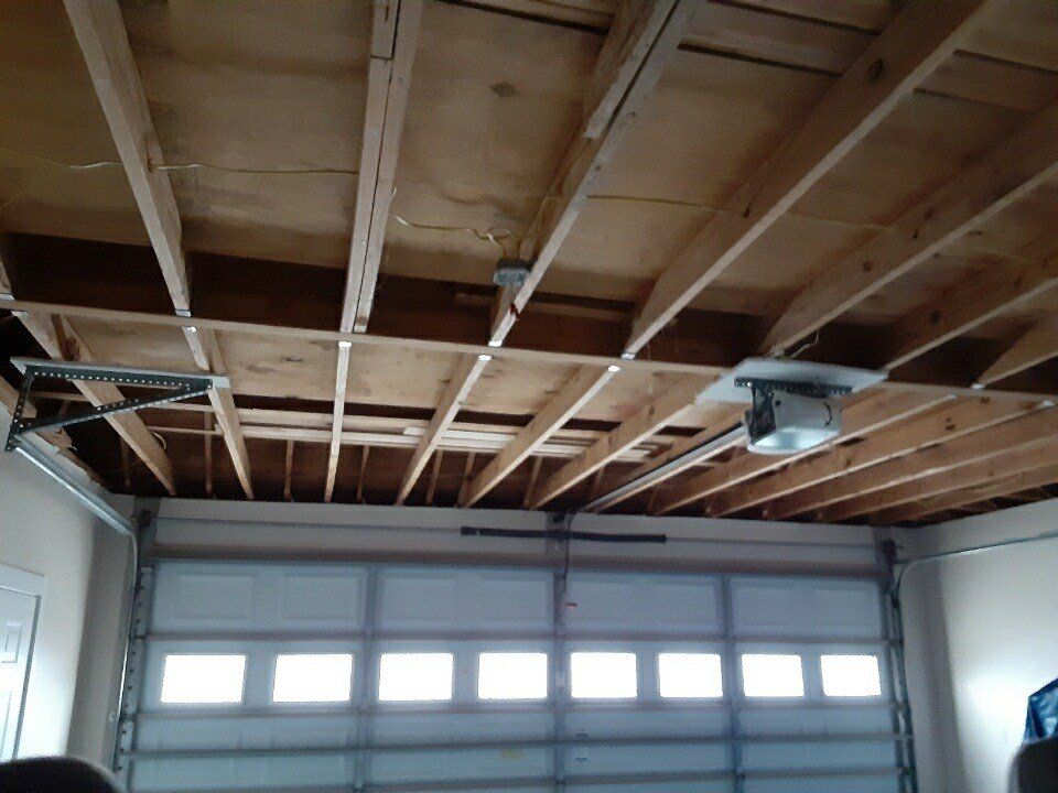 Garage ceiling with exposed wooden rafters and a garage door below with small windows
