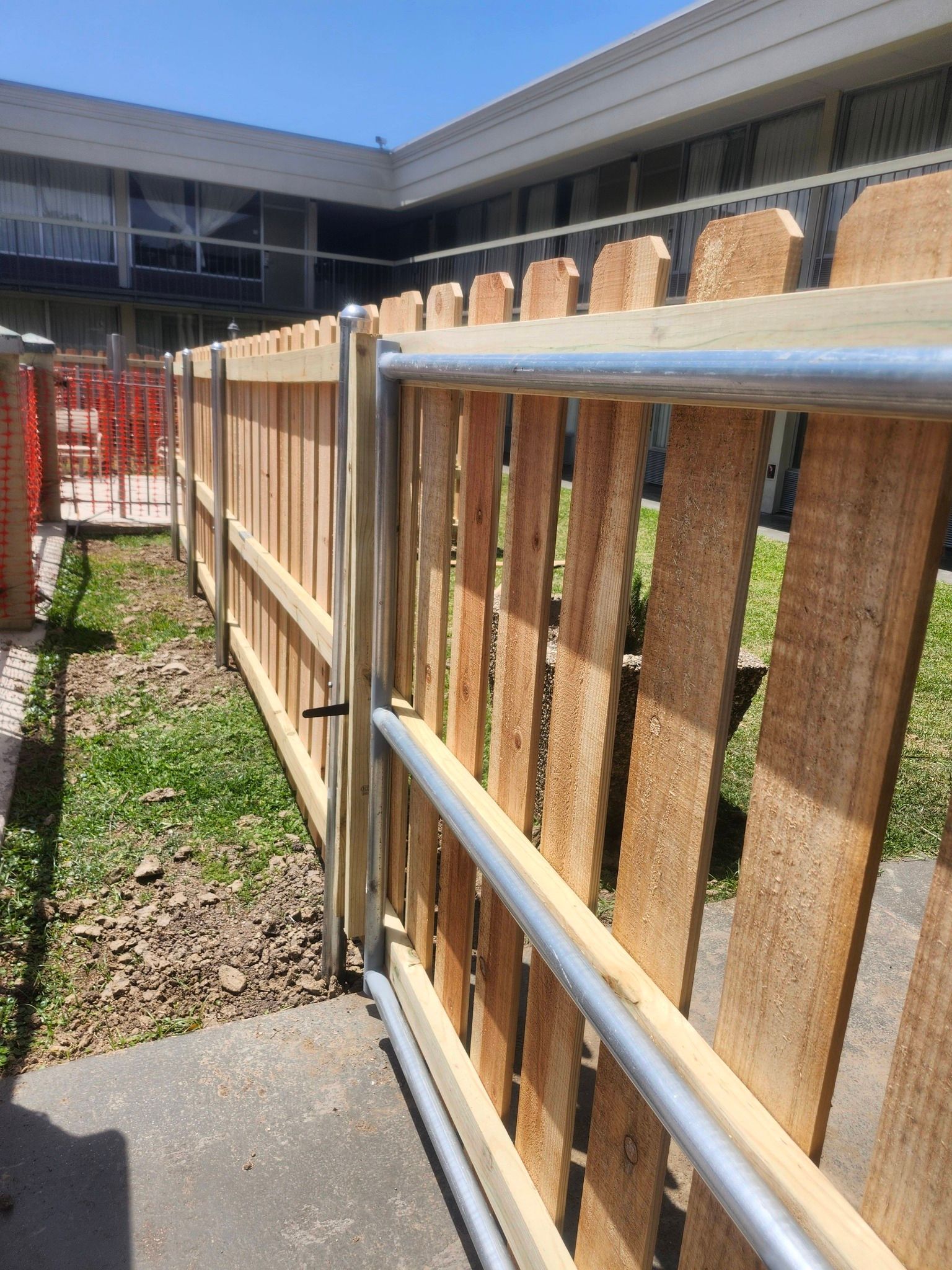 Wooden fence beside a concrete walkway in a sunny apartment courtyard