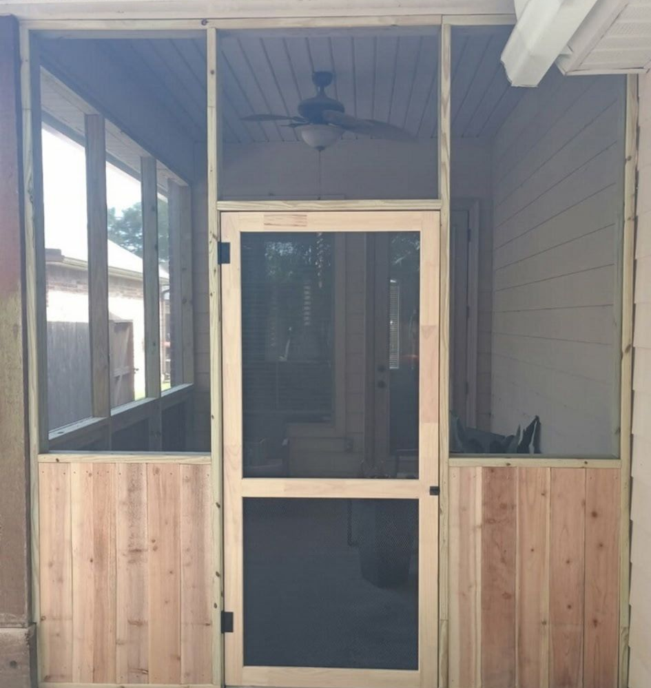Front porch with a screened door and wooden paneling on a house exterior