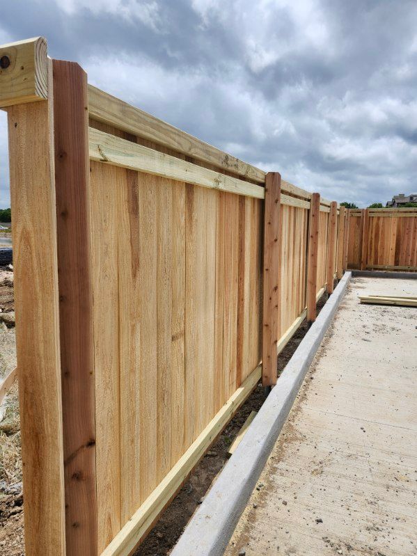 Wooden privacy fence along a concrete walkway under a cloudy sky