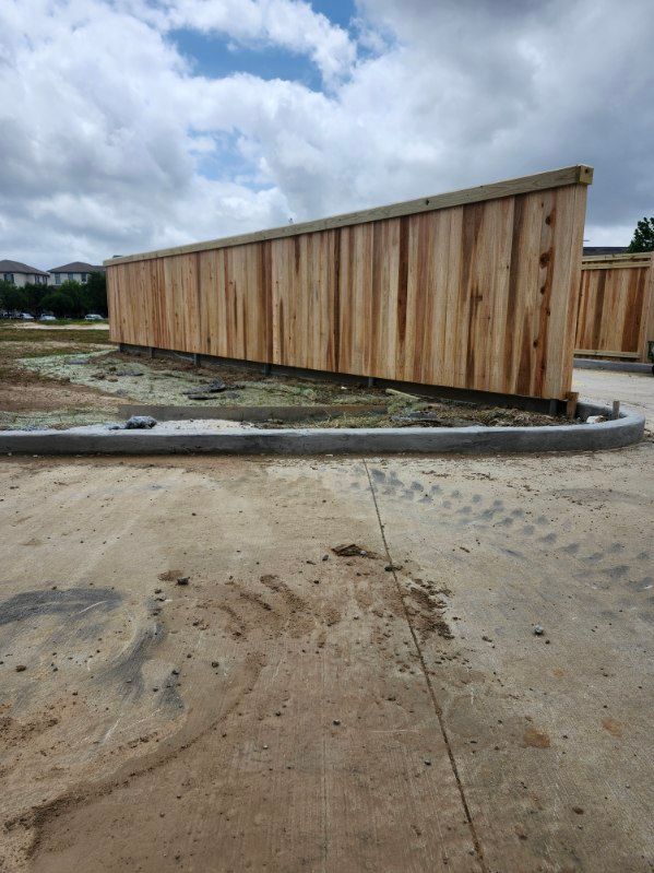 Wooden fence beside a muddy construction site under a cloudy sky