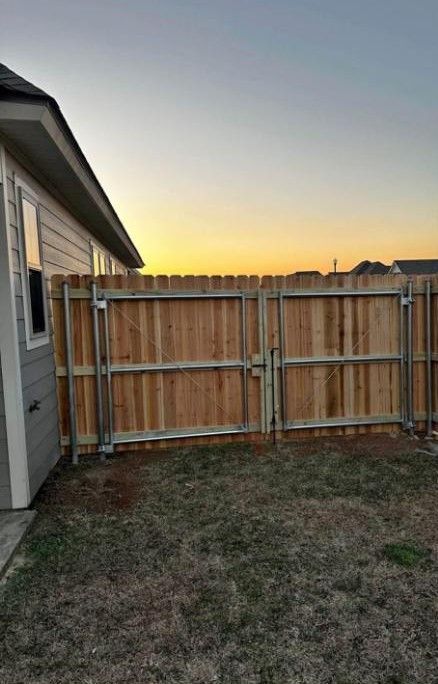 Backyard with wooden fence and small house exterior at sunset