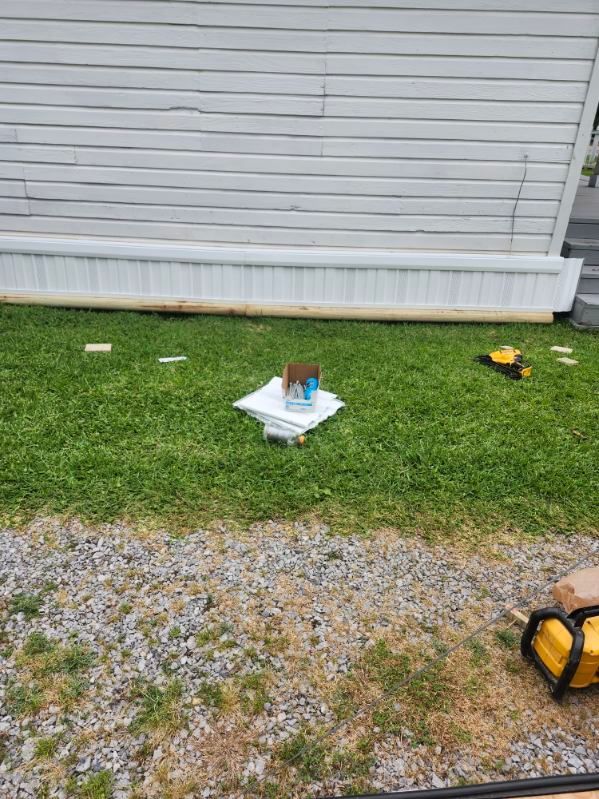 Small outdoor utility boxes on grass beside a white-sided building and gravel path.