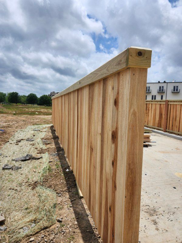 Wooden construction fence along a concrete slab at a building site under a cloudy sky