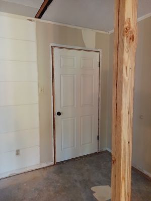 Small unfinished room with white closet door, wood beam, and concrete floor.