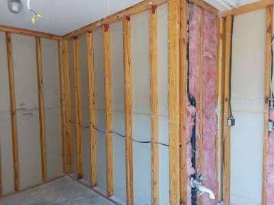 Partially demolished room with exposed wall studs and pink insulation.