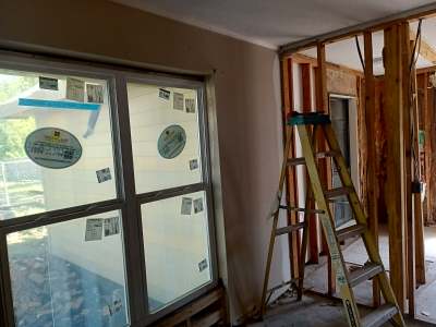 Room under renovation with a window, ladders, and exposed wall framing