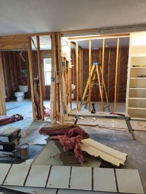 Partially renovated room with exposed studs, tools, and debris on the floor