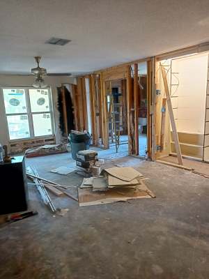 Home renovation with exposed studs, drywall, tools, and debris on the floor.
