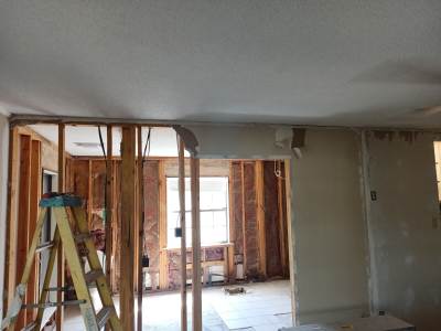Renovation site with exposed studs, ladder, and unfinished walls in a bright room