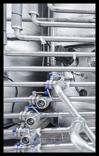 A row of stainless steel pipes and valves in a factory.