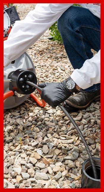 A plumber wearing black gloves is working on a pipe in Phoenix.