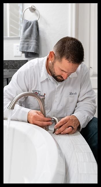 A plumber is fixing a faucet in a bathroom.