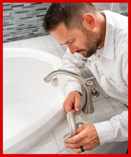 A plumber is fixing a faucet in a bathroom.