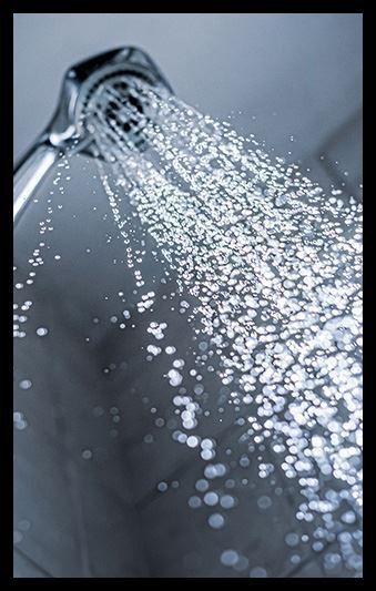 A close up of a shower head spraying water