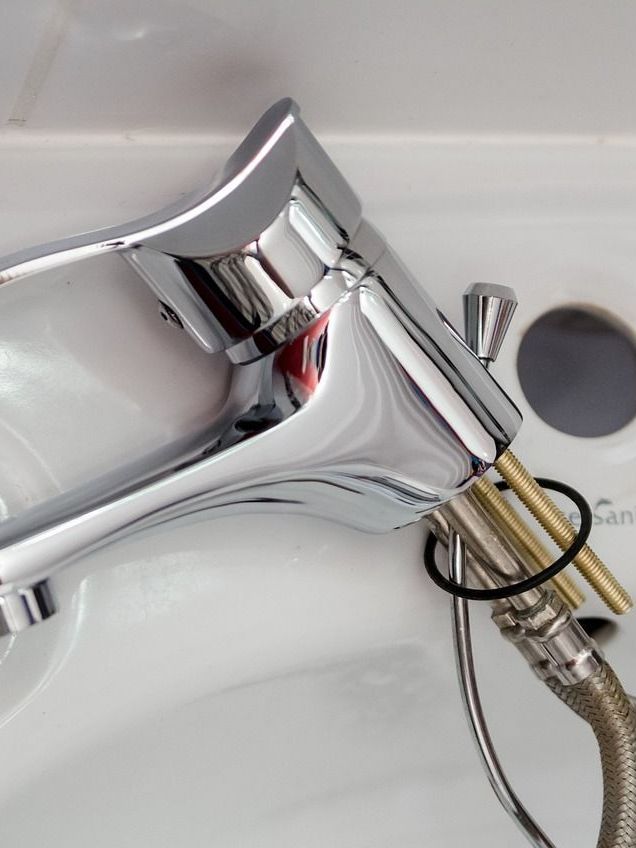 Chrome faucet with exposed supply lines, sitting in a white sink.