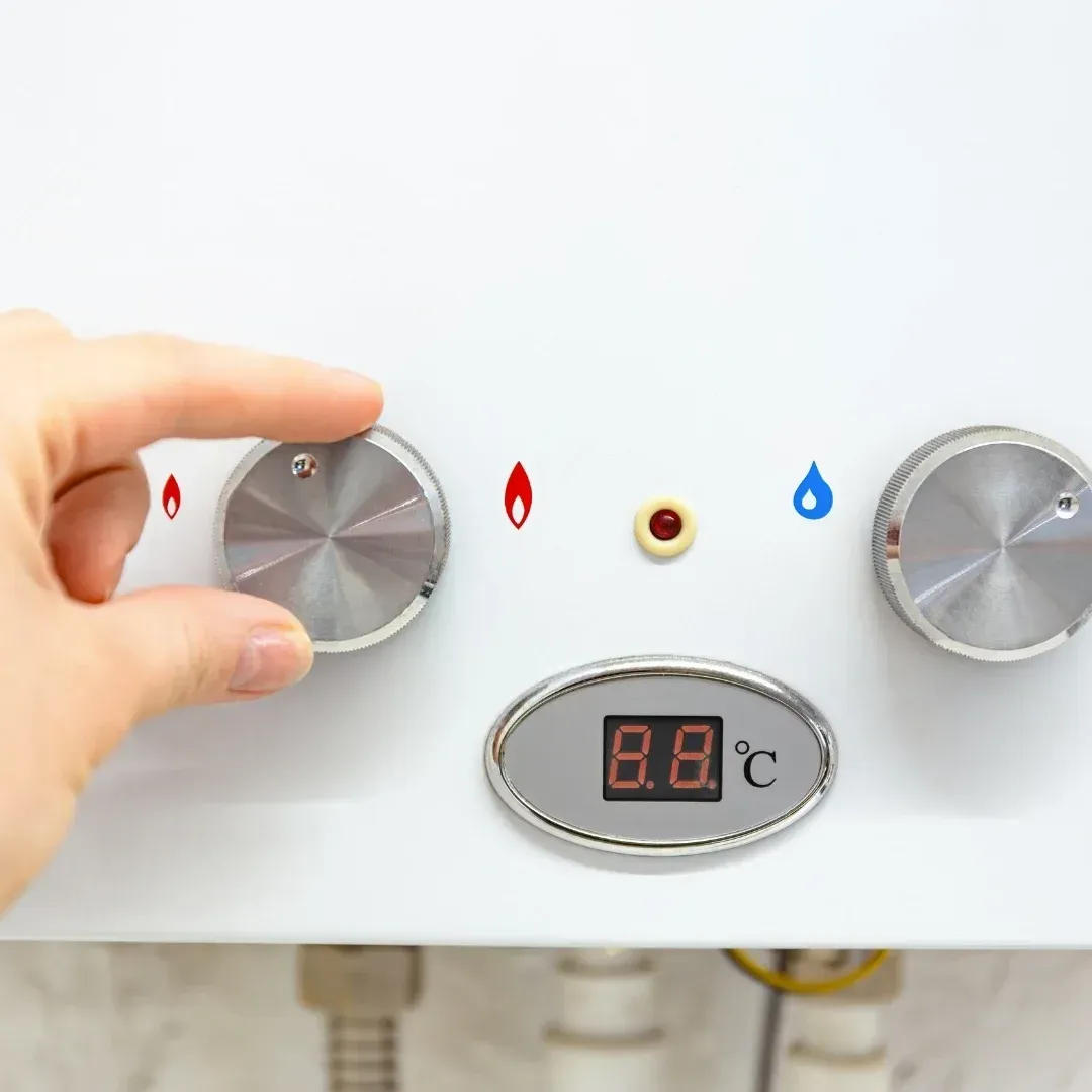 Hand turning a silver control knob on a water heater
