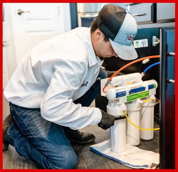 A plumber based in Arizona is working on a water filter in a kitchen.