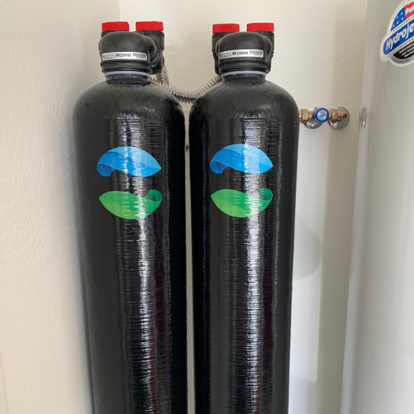 Two black cylinders with blue and green logos on them are hanging on a wall.