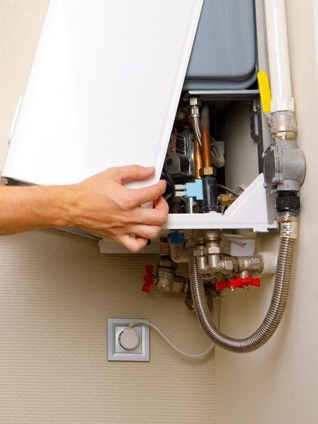 A plumber is fixing a water heater in a bathroom.