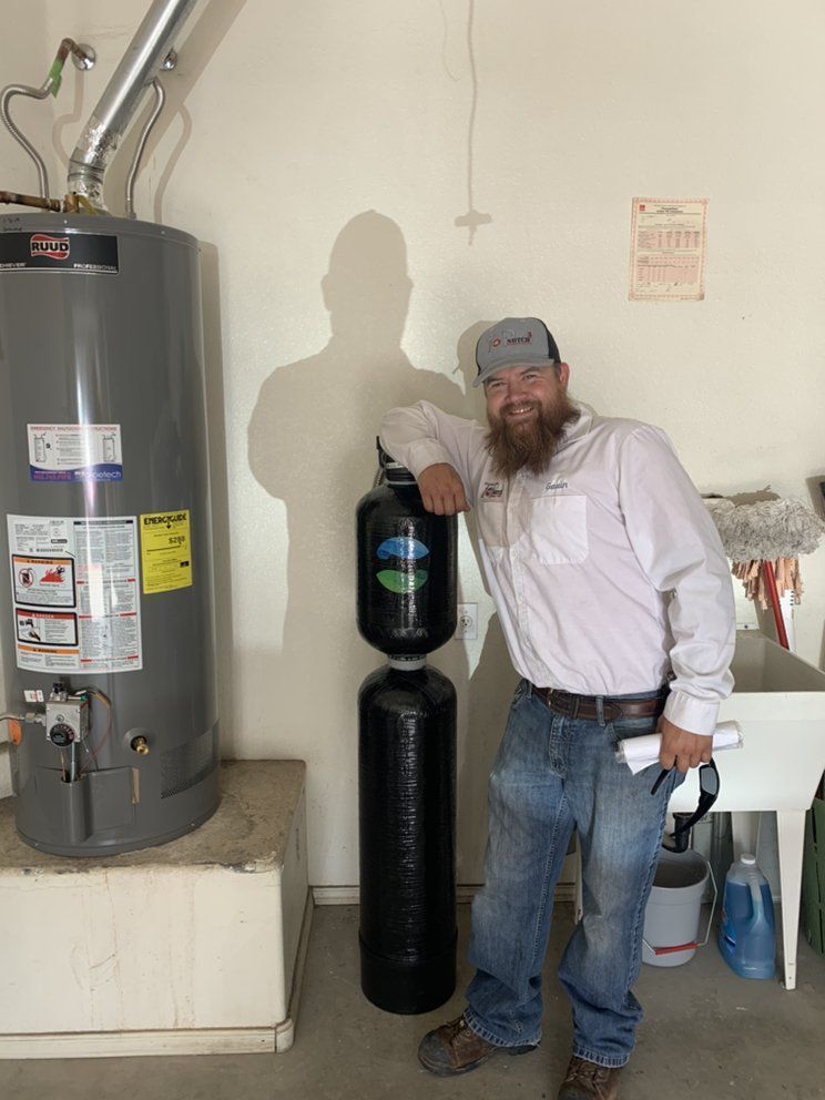 A man with a beard is standing next to a water heater.