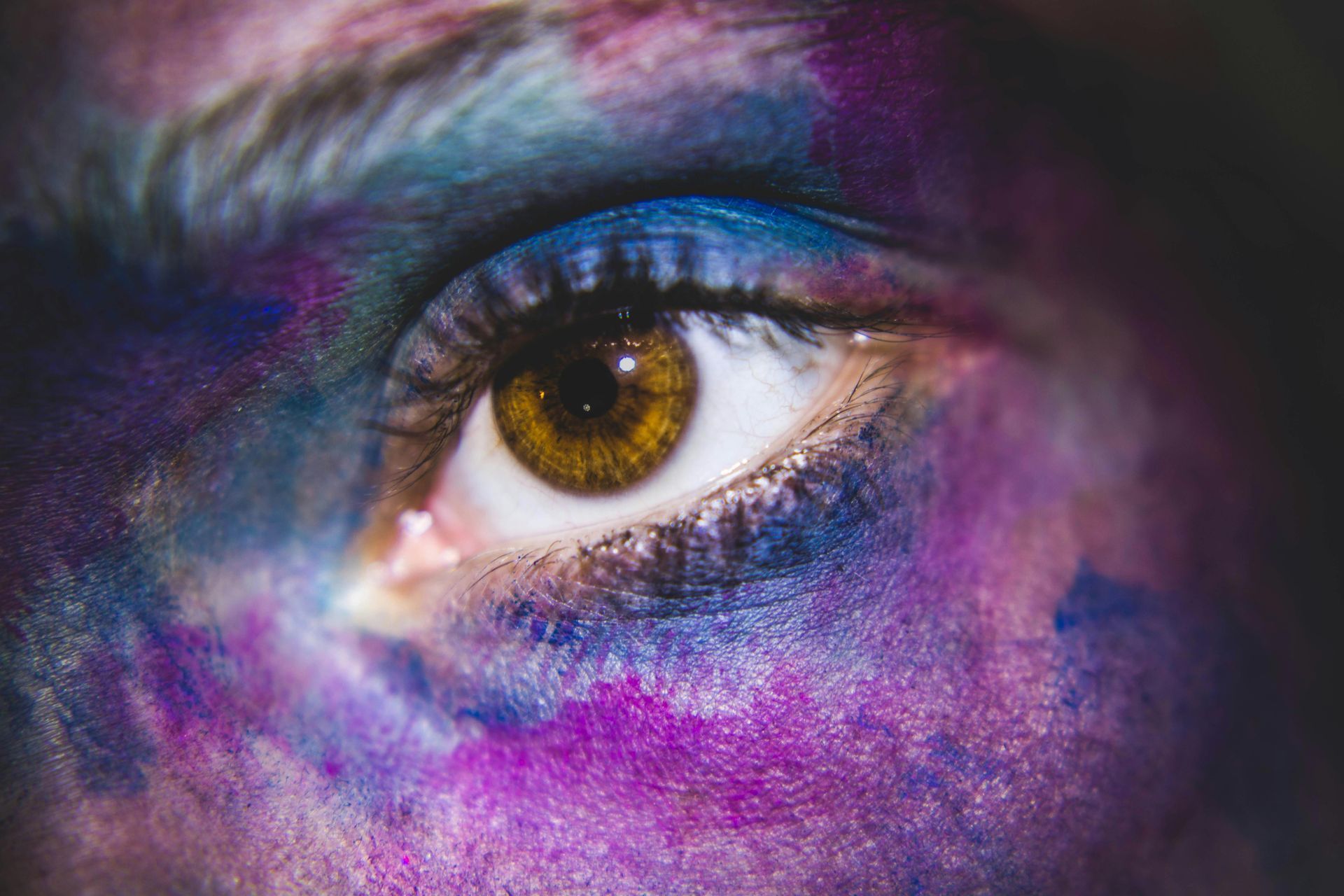 A close up of a woman 's eye with purple and blue makeup.