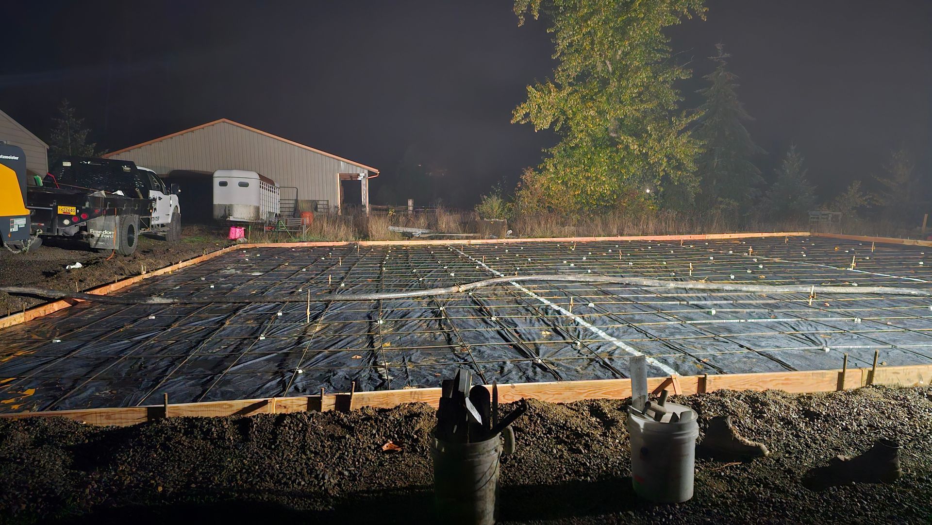 A construction site at night with a building in the background.