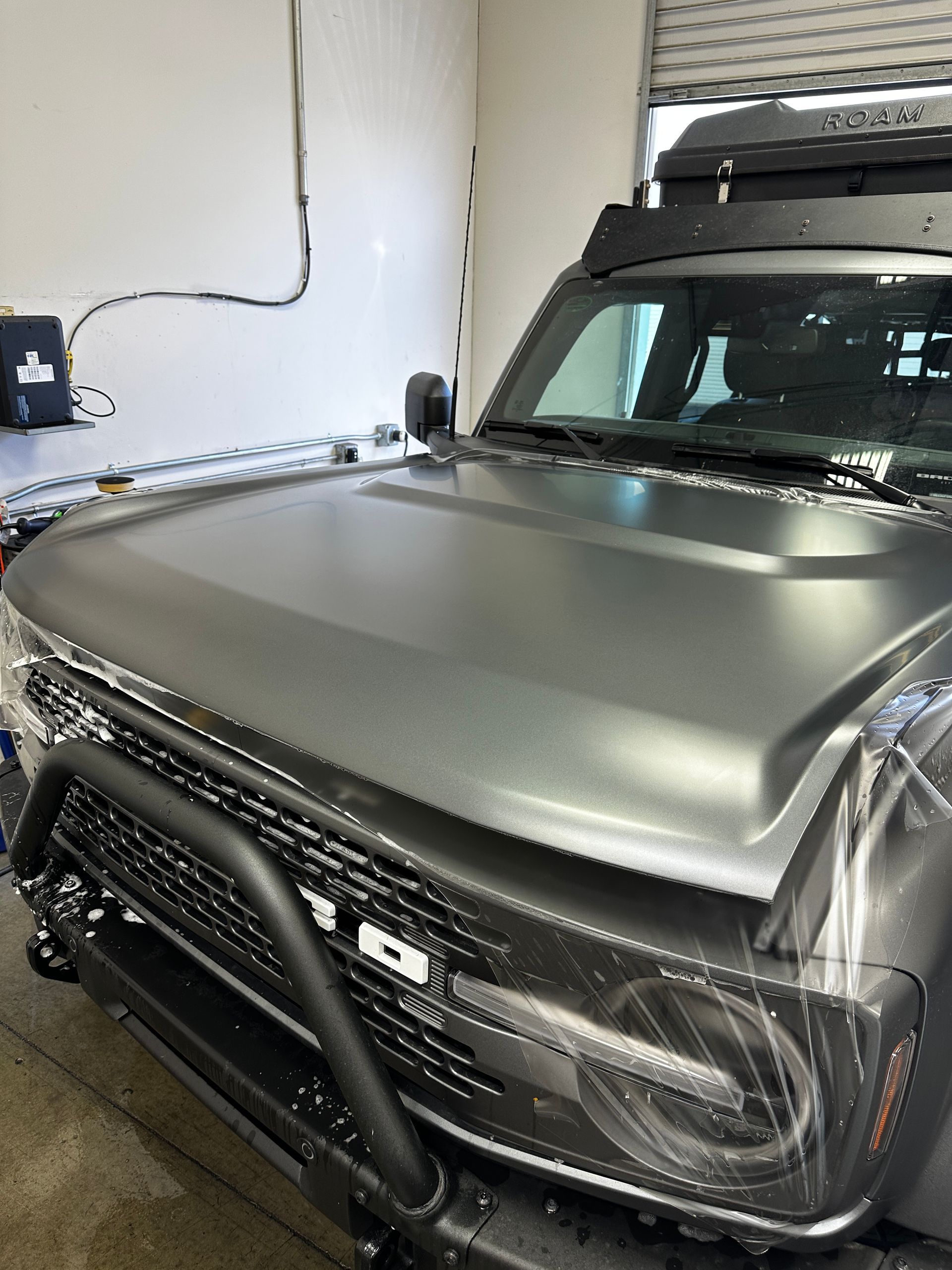 A gray ford bronco is parked in a garage.