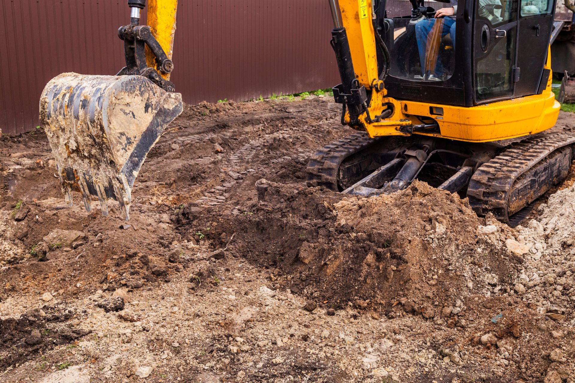 A construction worker is standing in front of a bulldozer at a construction site.