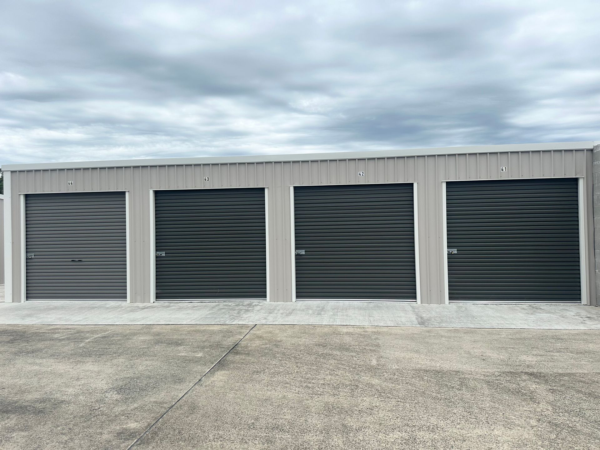 A row of storage units with black doors on a cloudy day.— Coolabah Self Storage In Taree, NSW