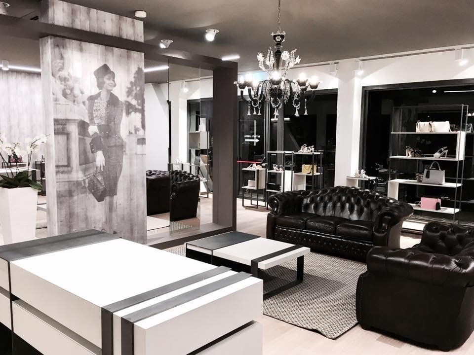 Salotto moderno in bianco e nero con divani, tavolini, lampadario e un grande poster di moda.
