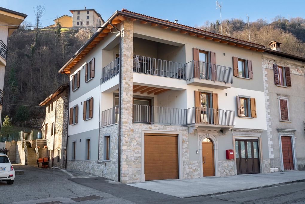 Casa in pietra bianca con persiane in legno e balconi in una strada stretta al crepuscolo