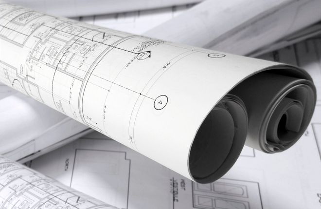 Planimetrie architettoniche arrotolate con disegni tecnici su una scrivania