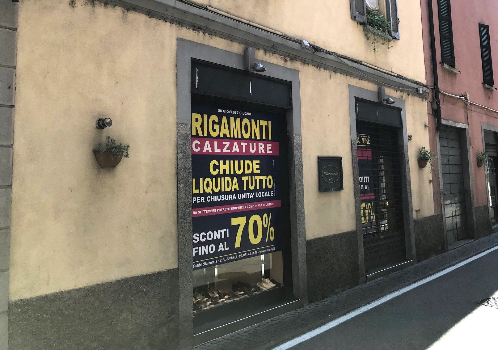 Negozio di scarpe chiuso con insegne di saldi gialle e nere su una strada stretta